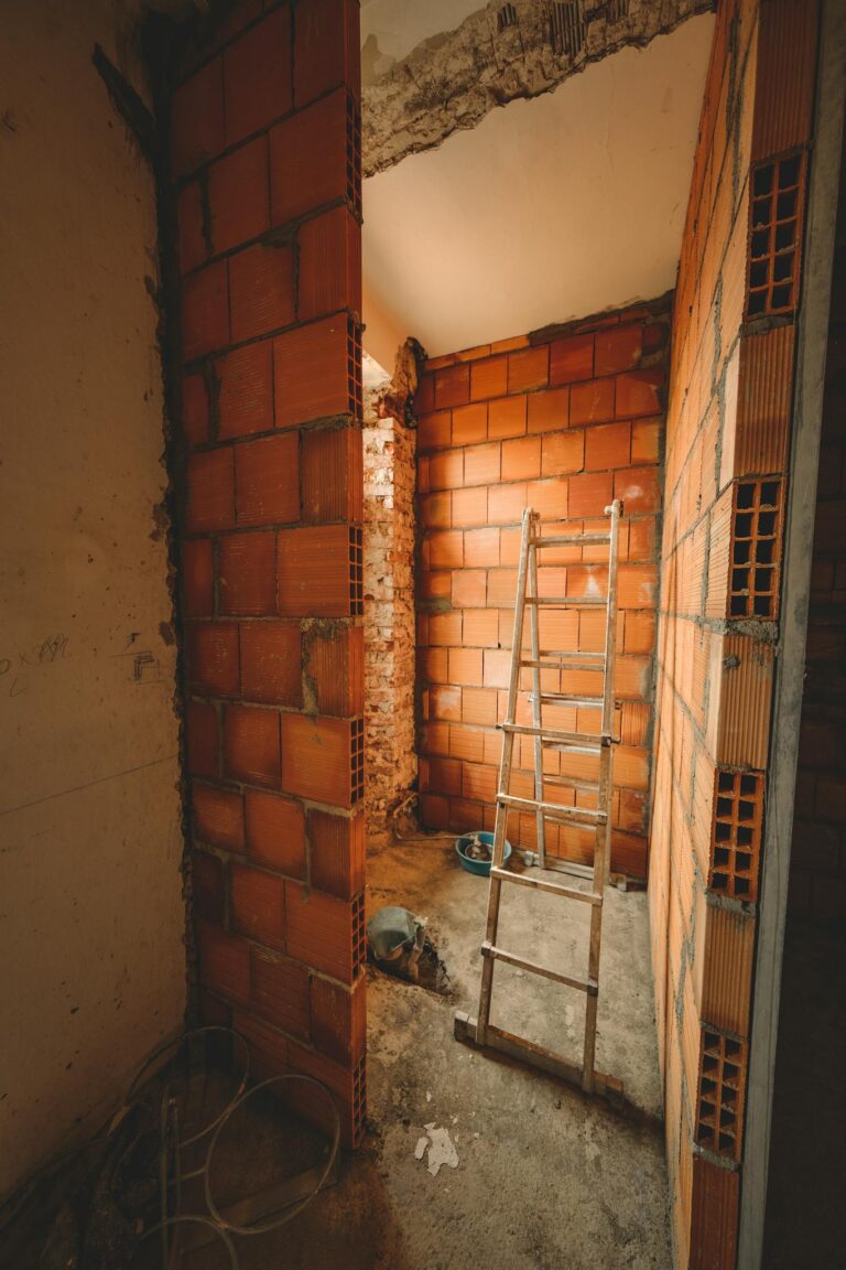 A construction site with a ladder leaning against red brick walls, showcasing renovation activities.